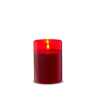 Glass red pillar candle lit inside a cylindrical glass holder, 3.5x5 inches