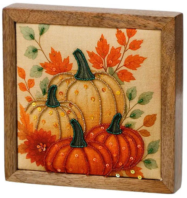 Beaded orange pumpkin block by Special T in a wooden frame, featuring two pumpkins with green stems and autumn leaves.