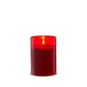 Glass red pillar candle lit inside a cylindrical glass holder, 3.5x5 inches