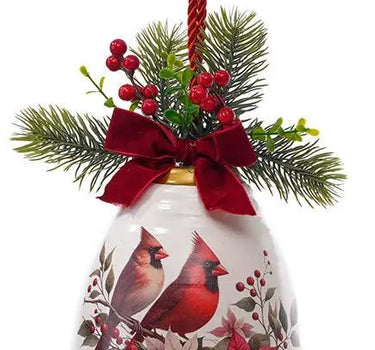 Metal cardinal bell ornament by Special T; white bell with cardinal and poinsettia motif, red bow, greenery, and hanging red cord.